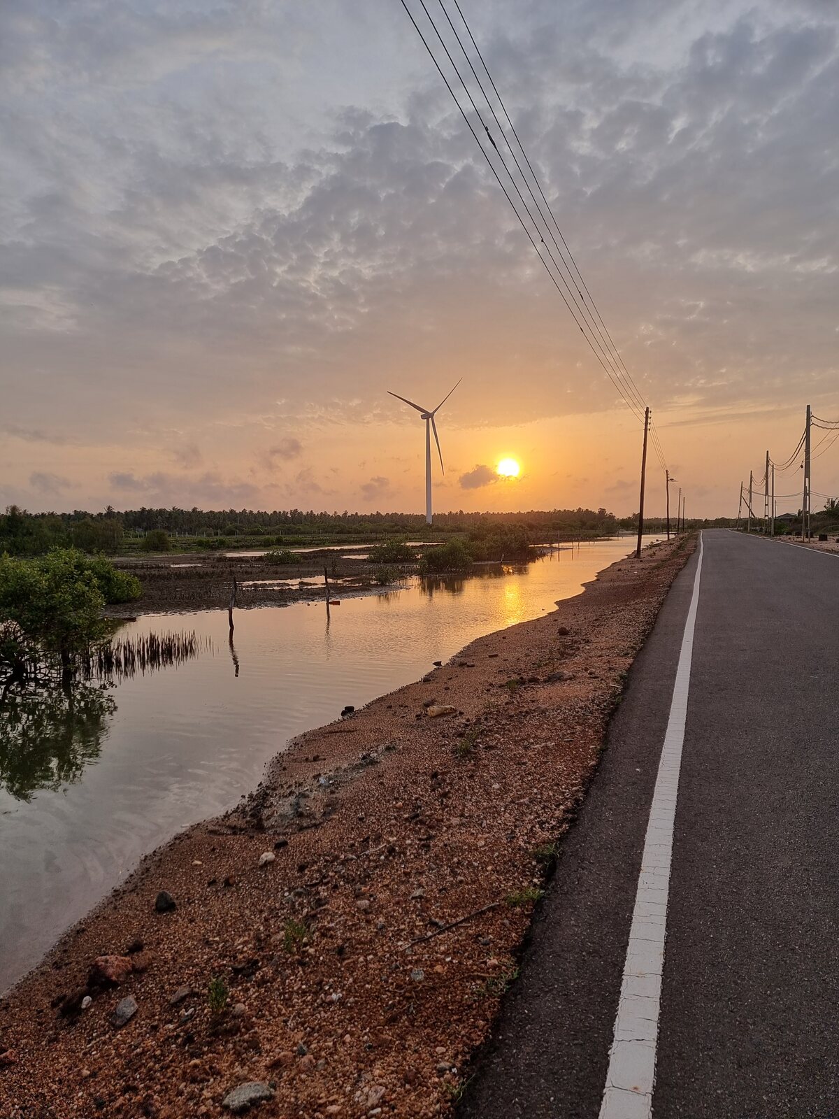 Sunset over a coastal road with wind turbines, Sri Lanka