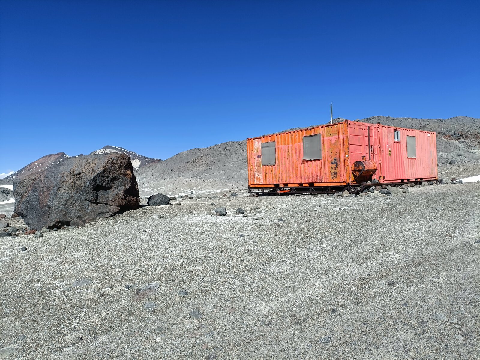 Refugio Tejos, a red steel shelter on the grey volcanic slope